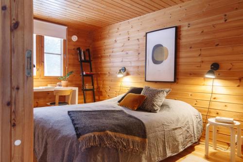 ein Schlafzimmer mit einem Bett in einer Holzwand in der Unterkunft Katve Nature Retreat in Kirkkonummi