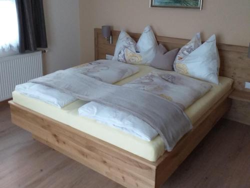 a large wooden bed with white sheets and pillows at Ferienwohnung-Nassfeld-Haus Umschaden in Tröpolach