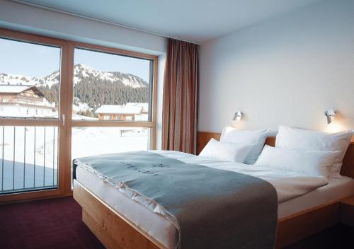 - une chambre avec un grand lit et une grande fenêtre dans l'établissement Hotel Alpenstern, à Damüls