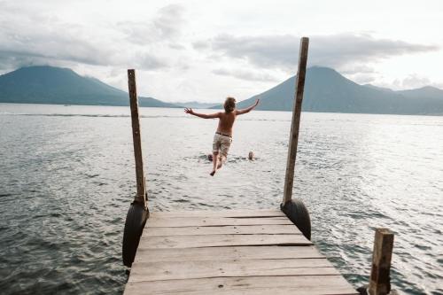 a man jumping off a dock into the water at Hotel La Casa del Mundo in Jaibalito