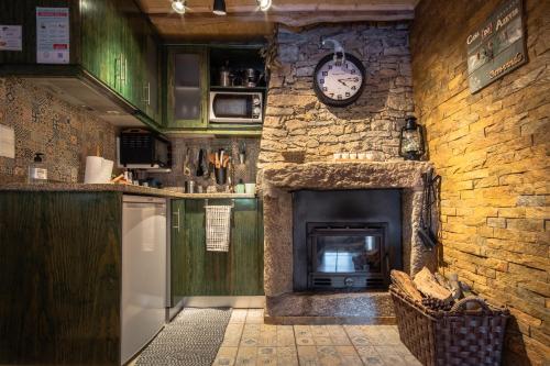 a kitchen with a fireplace and a clock on the wall at Casa do Azevim in Gavieira