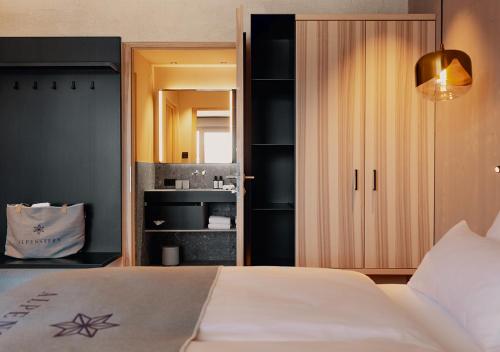 a bedroom with a white bed and a bathroom at Alpenstern Genießerhotel in Damuls