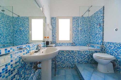 uma casa de banho em azulejos azuis com um lavatório e um WC em Spaccanapoli Comfort Suites em Nápoles