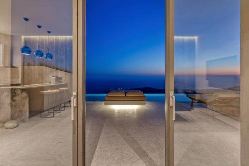 a bathroom with a view of the ocean through a glass door at Santorini Sky, Luxury Resort in Pyrgos