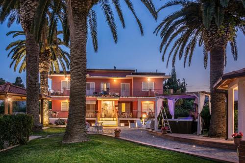 dom z palmami na dziedzińcu w obiekcie Hotel Villa Rosa w mieście Porto Azzurro