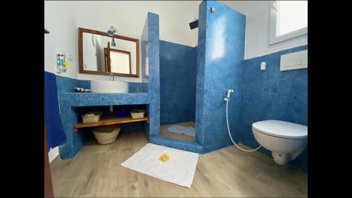 a blue bathroom with a toilet and a sink at Villa Thamani Zanzibar in Pwani Mchangani