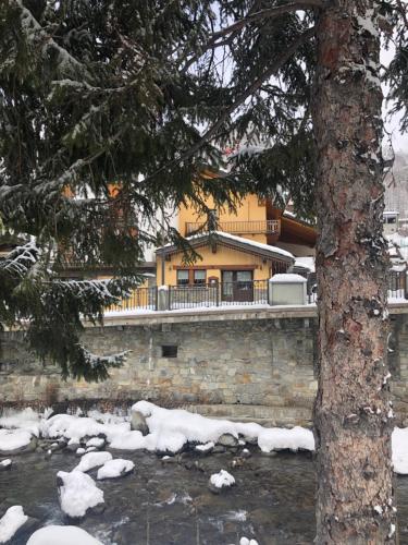 a building in the snow next to a river at Hotel Coeur Du Village in La Thuile