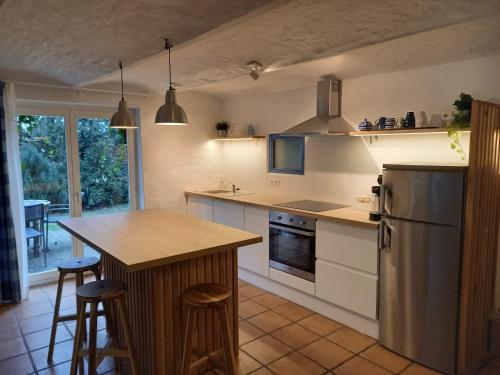 a kitchen with white cabinets and a island with bar stools at Gîte La Maison du Vieux Pommier in Spa