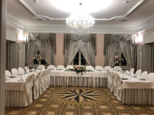 un salón de banquetes con mesas y sillas blancas y una lámpara de araña en Hotel Pałac Borynia, en Jastrzębie-Zdrój