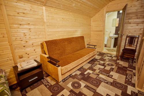 Habitación con sofá en una habitación de madera en Villa Na uzlissi, en Migovo