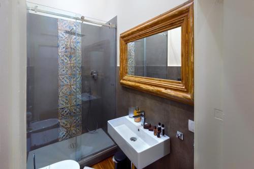 a bathroom with a sink and a mirror and a shower at Naca Suite in Catania