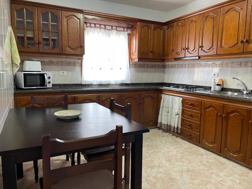 kuchnia z drewnianymi szafkami, stołem i kuchenką mikrofalową w obiekcie Casa Feluca w mieście Breña Alta