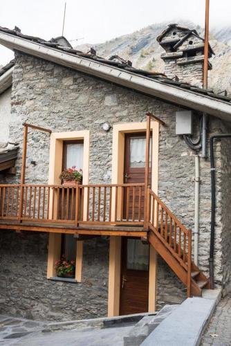 a stone building with a wooden balcony on it at Hotel Coeur Du Village in La Thuile