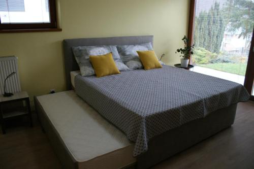 Un dormitorio con una cama con almohadas amarillas y una ventana en Apartmány Kvetná en Rajecké Teplice