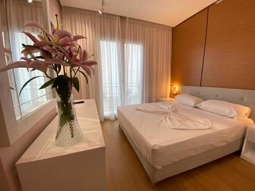 a bedroom with a bed and a vase of flowers on a table at Hotel Edart in Durrës