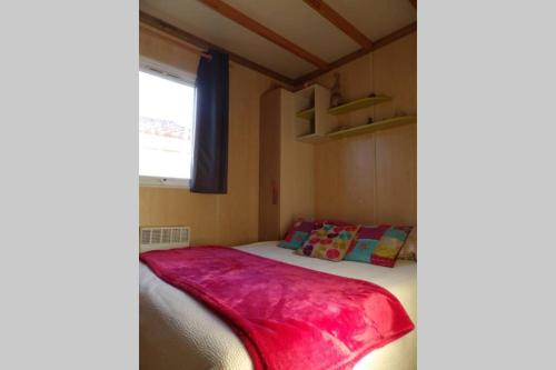 ein Schlafzimmer mit einem Bett mit einer roten Decke darauf in der Unterkunft Châlet dans parc de loisirs 5 étoiles in Puget-sur Argens