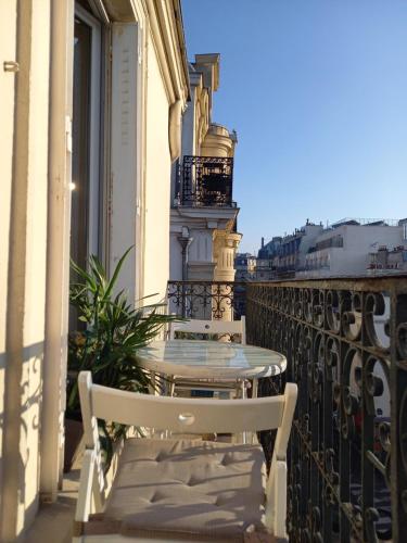 une table et des chaises sur le balcon d'un bâtiment dans l'établissement Appartement avec balcon au cœur PARIS, à Paris