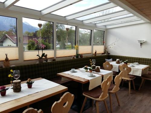 a dining room with tables and chairs and windows at Gästehaus Pöppl in Unterwössen