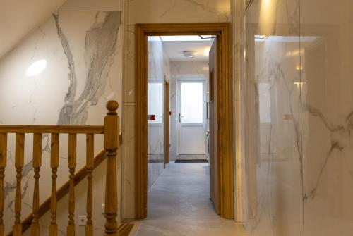 a hallway with stairs and a marble wall at Burren London Hotel in London