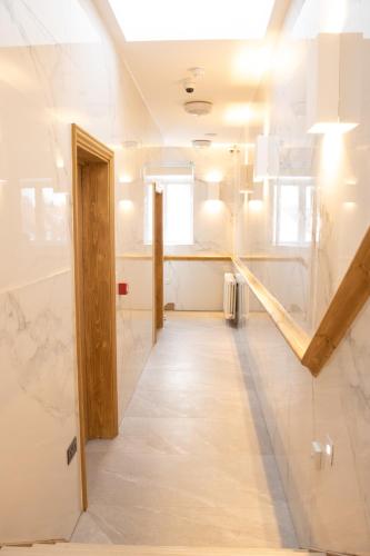 a room with a hallway with white marble walls and a staircase at Burren London Hotel in London