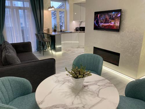 a living room with a table and chairs and a tv at Panorama Luxury Apartment in The House with a Spire, a historical building in the city centre in Kharkiv