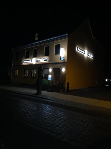 a building with neon signs on the side of it at night at Gaststätte & Pension Pommernstube in Gartz an der Oder