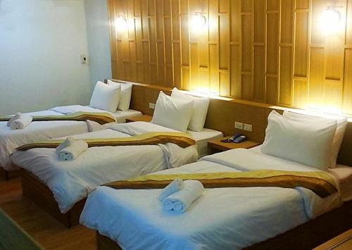 a hotel room with three beds with white sheets at King Royal Garden Inn in Bangkok