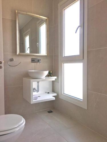 a white bathroom with a sink and a window at Apart Amabile Sul Mare in Villa Gesell