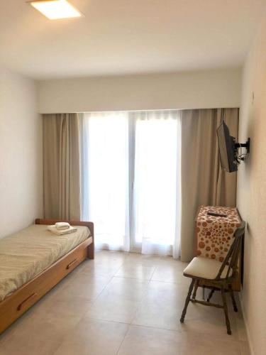 a bedroom with a bed and a chair and a television at Apart Amabile Sul Mare in Villa Gesell