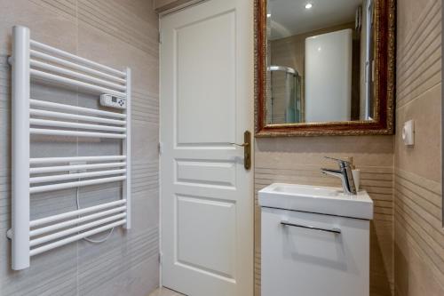 La salle de bains est pourvue d'une porte blanche et d'un lavabo. dans l'établissement StayLib - Lovely 2 rooms porte de Montmartre, à Saint-Ouen