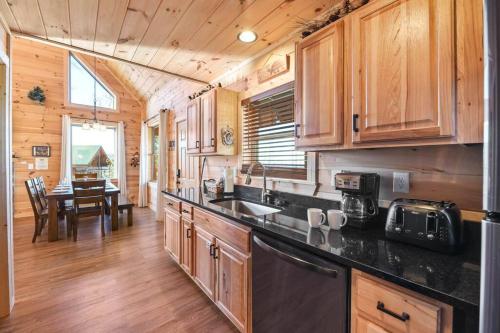 a kitchen with wooden cabinets and a dining room with a table at Walnut Ridge Cabin. Sleeps 7-11! Hot tub, pool table, minutes to downtown Gatlinburg! in Gatlinburg