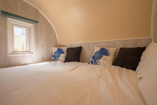 sypialnia z białym łóżkiem z poduszkami i oknem w obiekcie The Hobbit w mieście Newmilns