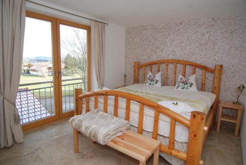 een slaapkamer met een houten bed en een balkon bij Bio Ferienhof Heiler in Feldkirchen-Westerham