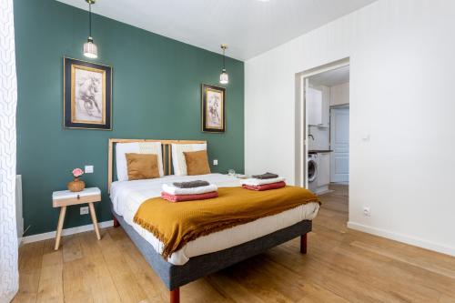 une chambre avec un lit avec un mur bleu dans l'établissement StayLib - APPARTEMENT 2 PIECES AUX PORTES DE PARIS, à Saint-Ouen