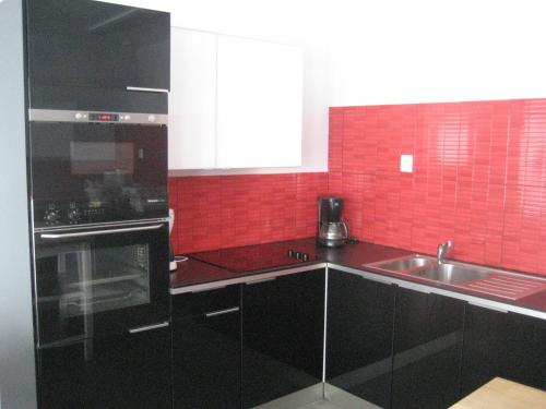 a kitchen with black counters and red tiles at Hjälmargården in Läppe