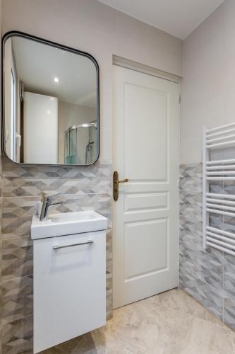 une salle de bain avec un lavabo blanc et un miroir dans l'établissement StayLib - APPARTEMENT 2 PIECES AUX PORTES DE PARIS, à Saint-Ouen