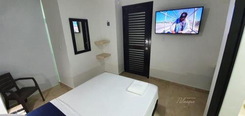 Habitación pequeña con cama y TV en la pared. en Palmagua, en Barranquilla