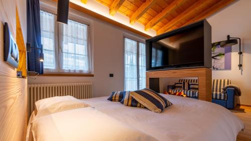a bedroom with a white bed with a flat screen tv at Sport Hotel Alpina in Madesimo