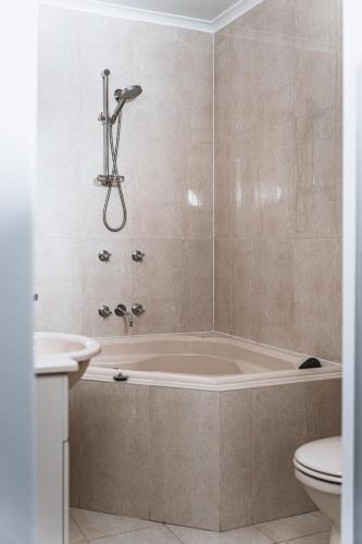 a bathroom with a tub and a toilet and a sink at Daylesford Spa Accommodation in Daylesford