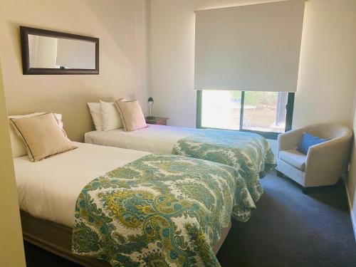 a hotel room with two beds and a chair at Adelphi#5 in Echuca