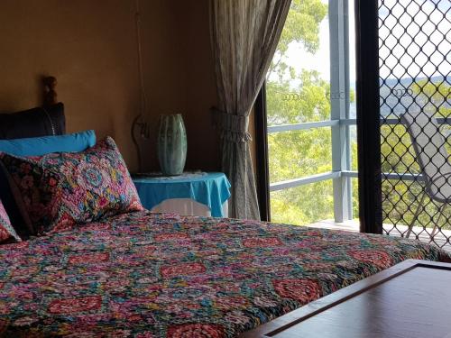 a bedroom with a bed next to a window at Mapleton Peaceful Provence BnB in Mapleton