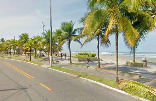una calle con palmeras en la playa en Apartamento aconchegante 1 quadra da praia en Praia Grande