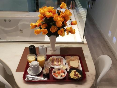 a tray of food on a table with a vase of flowers at A2 suites - Hotel e Motel in Brasilia