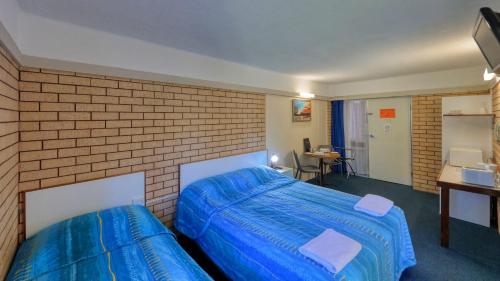 two beds in a room with a blue wall at Binalong Motel in Goondiwindi