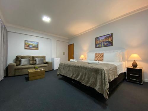 a bedroom with a large bed and a couch at Quarto Luxo Silver in Anápolis