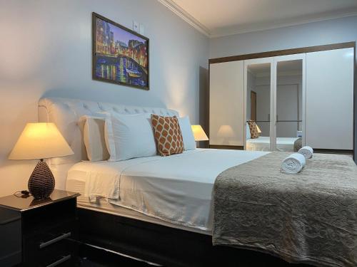 a bedroom with a large white bed with a lamp at Quarto Luxo Silver in Anápolis