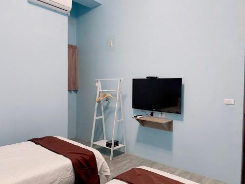 a room with a bed and a tv on a wall at Mo Dou Homestay in Taitung City