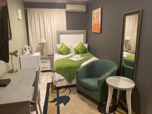 a bedroom with a bed and a chair and a mirror at Marion Lodge in Johannesburg