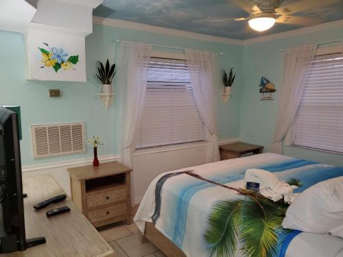 a bedroom with a bed and a desk and windows at The Monterey Beach Resort in St Pete Beach