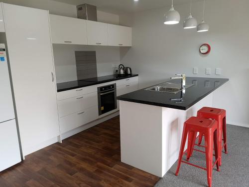 a kitchen with a black counter and a red stool at Stony Creek, 3 bedroom home, Franz Josef in Franz Josef
